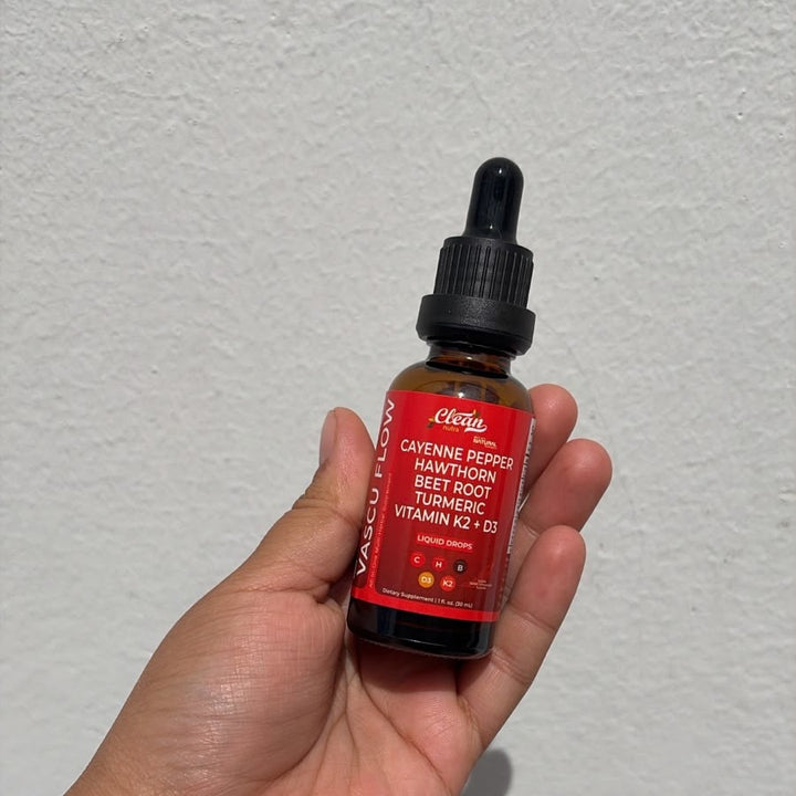 Frasco real de Vascu Flow 30 ml en la mano: etiqueta roja con cayena, espino blanco, remolacha, cúrcuma y vitaminas K2 y D3